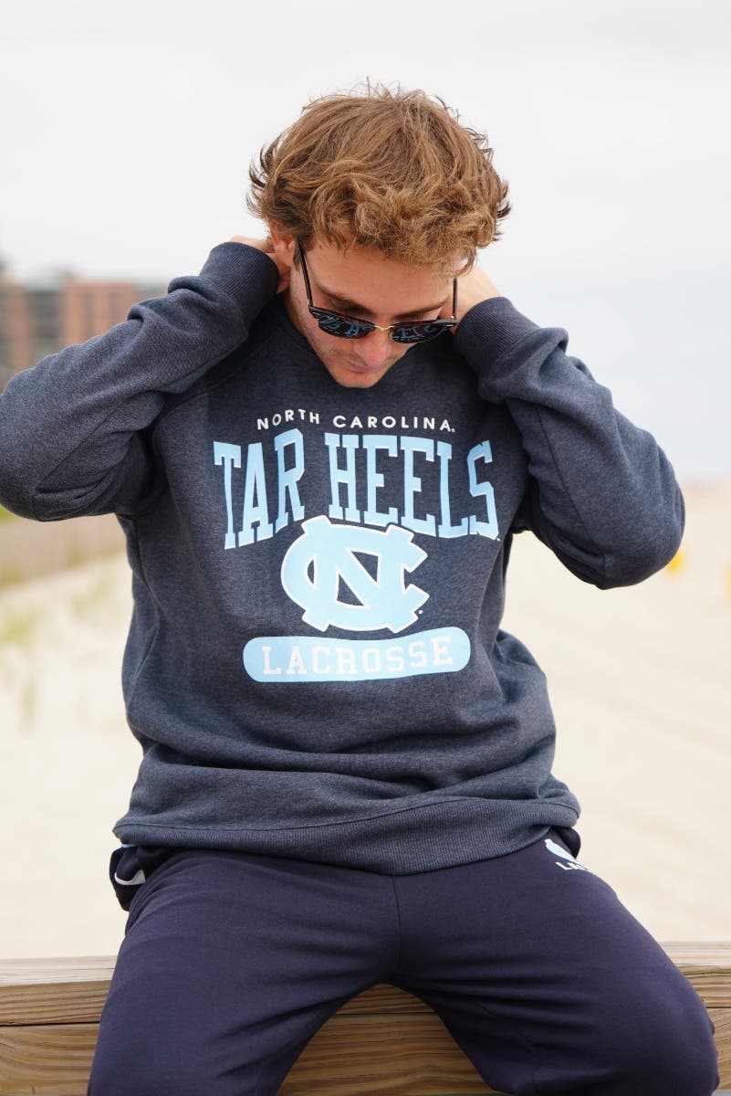 UNC Tar Heels Lacrosse Crew neck on model sitting on railing at the beach